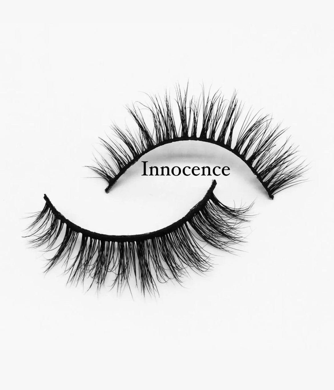 A pair of wispy, black Nayy Seduction Brand MesmerEyes Mink Lashes with densely packed strands is displayed on a white background. The word "Innocence" is written in an elegant font between the two lashes.